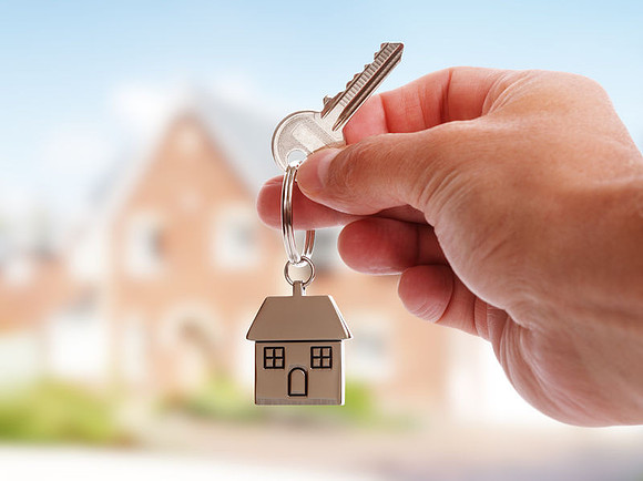Hand holding key on house and nature background